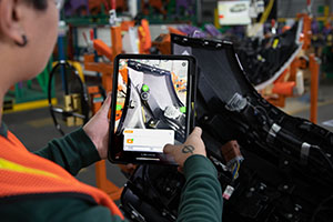 Manufacturing worker using a digital display beside production equipment